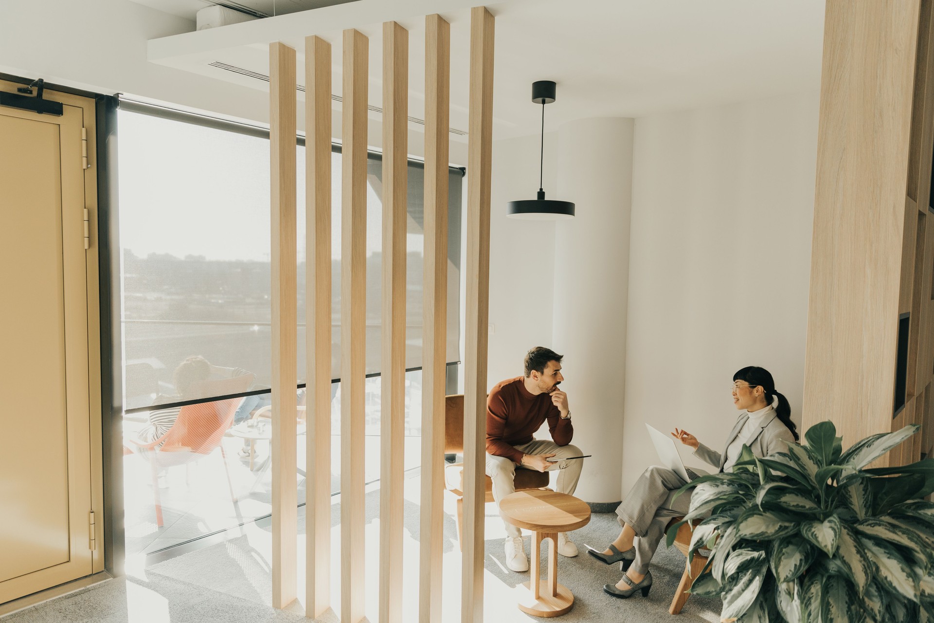 Engaging conversation unfolds inside a modern, stylish lounge with natural light filtering through